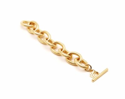 Un bracelet chaîne en or à gros maillons texturés et fermoir à bascule, doté d'une petite breloque ronde gravée des initiales « MK », représentées sur un fond blanc, évoque l'élégance parisienne intemporelle.
