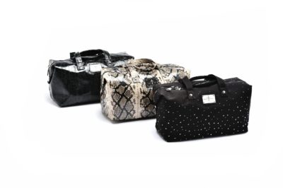Thomas Duclert, talentueux photographe parisien, a photographié trois sacs de voyage alignés sur un fond blanc. De gauche à droite : un sac noir en simili-crocodile, un sac beige à motif serpent et un sac noir orné de petits pois blancs en forme d'étoile. Chaque sac élégant est doté d'une poignée et d'une étiquette.